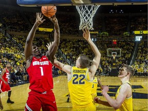 Ohio State forward Jae'Sean Tate (1) attempts a basket while defended by Michigan guard Duncan Robinson (22) and forward Moritz Wagner, right, in the second half of an NCAA college basketball game in Ann Arbor, Mich., on Feb. 18, 2018.