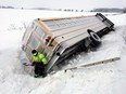 A tow truck operator works to remove a school bus from a ditch near the intersection of Old Malden Road and the 14th Concession in Essex County on Feb. 7, 2018.