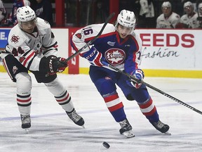 Akil Thomas, left, of the Niagara Ice Dogs and Chris Playfair of the Windsor Spitfires battle for the puck.