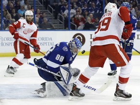 Tampa Bay Lightning goaltender Andrei Vasilevskiy (88) makes the save on a deflection by Detroit Red Wings right wing Anthony Mantha (39) during the first period of an NHL hockey game Thursday, Feb. 15, 2018, in Tampa, Fla. Red Wings' Henrik Zetterberg (40) looks for the rebound.