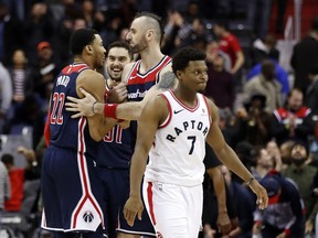 Washington Wizards forward Otto Porter Jr., left, forward Tomas Satoransky, from the Czech Republic, and center Marcin Gortat, from Poland, celebrate, as Toronto Raptors guard Kyle Lowry (7) heads off the court after an NBA basketball game Thursday, Feb. 1, 2018, in Washington. The Wizards won 122-119.