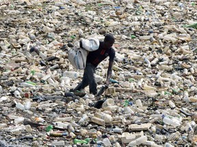 A man collects plastic from a waste water evacuation canal in Abidjan, Ivory Coast, on Feb. 19, 2018. The globe's oceans, lakes and rivers contain millions of tonnes of plastic waste.