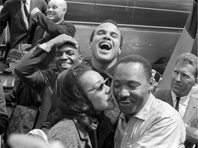 In this 1963 image released by HBO, Dr. Martin Luther King, Jr., right, receives a kiss from his wife Coretta Scott King as they appear in Alabama with Nipsey Russell, back row left, and Harry Belafonte. The image appears in the documentary "King in the Wilderness."