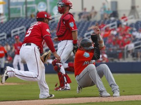 Miami Marlins' Starlin Castro (13) is tagged out by Washington Nationals third baseman Adrian Sanchez (5) after being caught in a rundown between third and home on a Lewis Brinson ground ball in the fifth inning of a spring training baseball game Tuesday, March 20, 2018, in West Palm Beach, Fla.