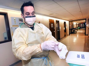 Mike Drouillard, a registered nurse at the Windsor Regional Hospital Ouellette campus puts on personal protective equipment on Monday, January 8, 2018, to guard against the influenza virus while interacting with a patient.