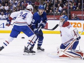 Montreal Canadiens goaltender Charlie Lindgren eyes the puck as Canadiens Michael McCarron (34) ties up Toronto Maple Leafs William Nylander during second period NHL hockey action in Toronto on March 17, 2018.