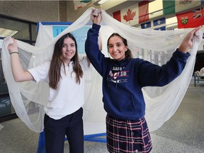 Gabby Botica, left, and Angela Hormiz, students at Holy Names High School in Windsor, pose with a mosquito net Wednesday, March 7, 2018. They raised $2,500 to buy the nets that will be sent to protect people against malaria in third world countries.