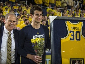 Michigan head coach John Beilein, left, stands with Austin Hatch, center, to honor Hatch's participation with the Michigan basketball team during senior day celebrations prior to an NCAA college basketball game against Ohio State at Crisler Center in Ann Arbor, Mich., Sunday, Feb. 18, 2018. Hatch is a two-time plane crash survivor, played for Michigan as a freshman, and has been a student assistant since 2015.