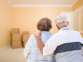 Hugging Senior Couple In Room Looking at Moving Boxes on the Floor