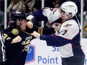 Windsor Spitfires' Tyler Angle (7) and Sarnia Sting's Jamieson Rees (39) fight in the first period of Saturday's Game 2 of their OHL Western Conference quarter-final at Progressive Auto Sales Arena in Sarnia. (Mark Malone/Chatham Daily News/Postmedia Network)