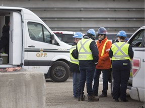 Workers at Prestressed Systems Inc. confer with each other after a fatal accident on the work site on April 12, 2018.