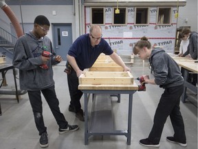 Grade 11 students, Maggie MacDonald and Jovaun Cooley, left, get instruction from Cory McAiney, centre, as they practice constructing a knee wall for an upcoming Habitat for Humanity home while at the Construction Academy based out of St. Joseph's Catholic High School on April 11, 2018.