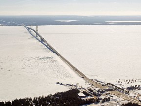 FILE - This Feb. 11, 2014, aerial file photo shows a view of the Mackinac Bridge, which spans a 5-mile-wide freshwater channel called the Straits of Mackinac that separates Michigan's upper and lower peninsulas. Sen. Gary Peters of Michigan said Friday, April 13, 2018, that the flow of crude oil through twin pipelines through the Straits should be suspended until authorities determine how severely they were damaged by what may have been a ship anchor strike. The Coast Guard is delaying action because of a heavy storm expected this weekend.