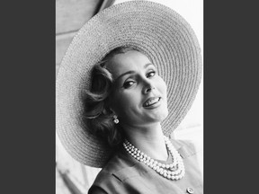 FILE - In a July 14, 1955, file photo, Zsa Zsa Gabor arrives at London Airport from Paris, in a Crimson dress and a straw hat. An auction of late actress Zsa Zsa Gabor's personal items, including scripts, costumes, jewelry and other items has earned more than $909,000. Heritage Auctions said Sunday, April 15, 2018, that the top seller at the two-day auction was a Margaret Keane portrait of the Hungarian-American actress, which sold for $45,000. (AP Photo/File)