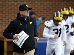 FILE - In this Nov. 11, 2017, file photo, Michigan coach Jim Harbaugh runs onto the field with his team before an NCAA college football game against Maryland in College Park, Md.