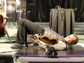 Fergus-based fiddle expert Scott Woods shows off one of his playing tricks - behind his back while on the floor - in April 2017.