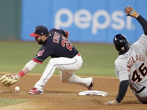 Cleveland Indians' Jason Kipnis, right, can't hold onto the ball as Detroit Tigers' Jeimer Candelario slides safely into second base for a double in the seventh inning of a baseball game, Tuesday, April 10, 2018, in Cleveland. Victor Reyes scored on the play.