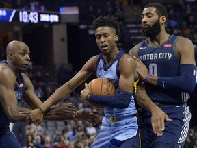 Memphis Grizzlies guard Kobi Simmons, center, drives between Detroit Pistons forward Anthony Tolliver, left, and center Andre Drummond (0) in the second half of an NBA basketball game Sunday, April 8, 2018, in Memphis, Tenn.