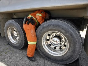In this file photo, Ministry of Transportation Officer Ken Clarke conducts truck safety inspections on June 26, 2012.