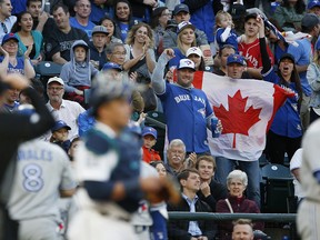 Fans hold the Canadian flag and cheer after Kendrys Morales #8 of the Toronto Blue Jays hit a two run home run in the fourth inning at Safeco Field on June 10, 2017 in Seattle, Washington.