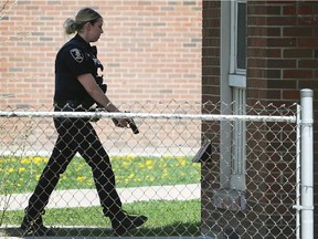 A Windsor Police officer, with her gun drawn, waits outside of a housing complex unit on Bloomfield Road on May 5, 2018 in Windsor. A man was assaulted at the residence.