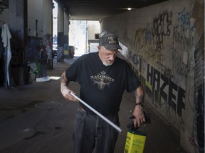 Roy Campbell, manager of harm reduction at the AIDS Committee of Windsor, walks through the alley behind the Pelissier Street parking garage picking up used needles used by drug users on May 8, 2018.
