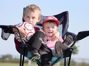 Madalayna Ducharme sits with her brother Henrik at Atlas Tube Centre soccer fields on Wednesday.