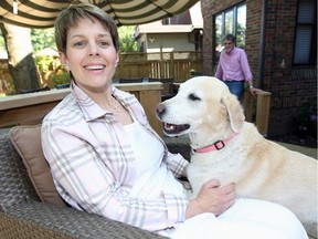 Anthrozoology Prof. Beth Daly, PhD, enjoys company of purebred labrador Grasshopper on her Walkerville patio June 11, 2018.  Daly's husband Jeff Cohen stands behind.