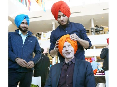 University of Windsor President Alan Wildeman is fitted for a turban by Dilpreet Singh, top, during Sikh Awareness and Turban Day at the University of Windsor on March 19, 2018.