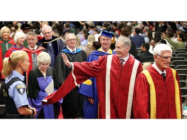 In one of his last convocations as University of Windsor President and Vice-Chancellor Dr. Alan Wildeman, centre, waves to graduates during the morning convocation May 30, 2018. University of Windsor Chancellor Edward Lumley, right, and other university officials walk from the stage to the reception area.