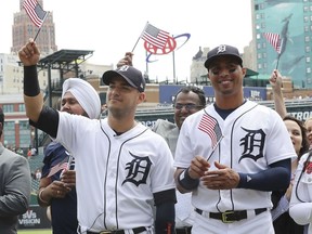 Detroit Tigers shortstop Jose Iglesias, left, and center fielder Leonys Martin wave an American flag after participating in a naturalization ceremony before a baseball game on June 25, 2018, in Detroit.