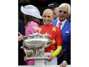 Jockey Mike Smith holds the August Belmont trophy after winning the Triple Crown and the 150th running of the Belmont Stakes horse race aboard Justify, Saturday, June 9, 2018, in Elmont, N.Y. Trainer Bob Baffert is at right.