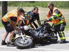 WINDSOR, ON. JUNE 11, 2018. --  Windsor firefighters and a police officer lift a motorcycle involved in a collision with an SUV on Monday, June 11, 2018. The accident occurred on Matchette Rd. near the entrance to Mic Mac Park at approximately 12:30 p.m. The male driver of the motorcycle suffered non-life threatening injuries.