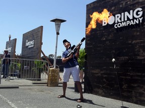 An attendee stands for a photograph while operating a Boring Co. flamethrower during the company's Not-a-Flamethrower Party outside of the Space Exploration Technologies Corp. (SpaceX) headquarters in Hawthorne, California, U.S., on Saturday, June 9, 2018.