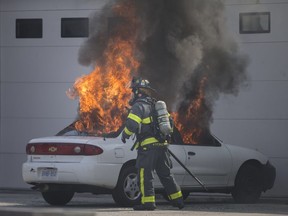 A firefighter with Windsor Fire and Rescue extinguishes a vehicle fire outside Granite Design Works at 1285 Crawford Ave., on June 17, 2018.