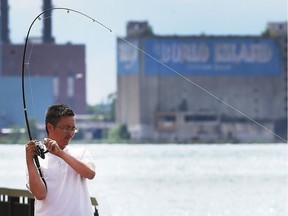 Jerry Yang fishes along the Detroit River on Wednesday, June 27, 2018 near the Ambassador Bridge.
