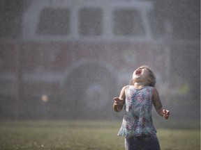 Eastlynd Manners, 3, lets the water fall onto her tongue as water falls from the ladder of a Windsor Fire and Rescue truck during the service's second week of Hot Summer Nights at Gary Dugal Park in Ford City, Thursday, July 28, 2018.