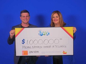 Michael and Rosalie Hebert of Tecumseh hold up the $1-million prize cheque they won from a Lotto MAX draw on May 25, 2018.