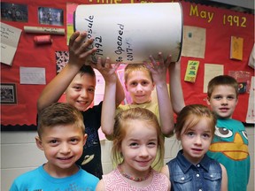 St. Rose Elementary School students recently opened a time capsule from 1992. Students from two families found photos of their respective Dads in the time capsule when they attended the school in the early nineties. From left, Aiden Samrah, 5, Evan Samrah, 8, Aubrey Langley, 6, Parker Langley, 10, Emerson Langley, 6, and Griffin Langley, 8, pose with the time capsule and photos on Monday, June 18, 2018.