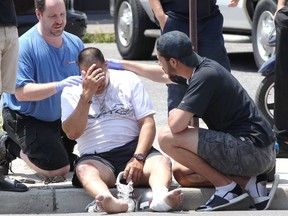 Paramedic graduate Hassan El-Hag, right, and another Good Samaritan, left, assist the injured driver of a BMW motor scooter who was involved in a two-vehicle crash on Wyandotte Street East at Louis Avenue on July 11, 2018. Essex-Windsor EMS paramedics soon arrived and transported the man to hospital with multiple abrasions and bruises. Windsor Police were investigating. The man's scooter was heavily damaged.