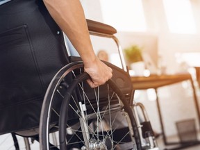 A man grabs the wheels on his chair in this photo illustration.