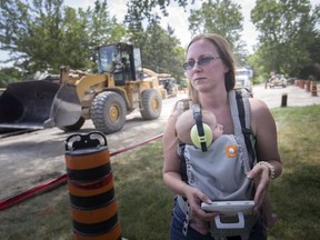 Kristen Aseltine holds four-month-old son, Bob Gibson, on her front lawn at 528 Sandison St., near where a new condominium development is being built, on July 10, 2018.