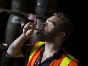 Toasting friendship. In this Oct. 4, 2017, file photo, Brock McLaughlin, from Brockstar Gaming in Toronto, takes a drink of 20-year-old whiskey at the J.P. Wiser's aging warehouse during a tasting tour.