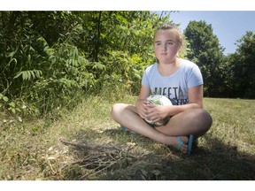 Lauren Godfrey, 9, sits next to a covered hole she fell in at Realtor Park, Monday, July 9, 2018.  The hole had nails attached to a wood board.
