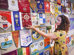 An exhibit focusing on 100 years of the Rotary Club of Windsor (1918) has opened at the Chimczuk Museum in Windsor. Exhibit curator Megan Meloche is shown on July 18, 2018, with a display of banners from Rotary members from around the world that were exchanged with local members.