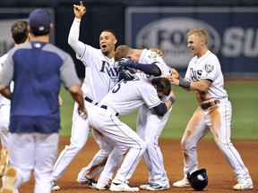 Tampa Bay Rays' Carlos Gomez, left, Matt Duffy (5) and Jake Bauers, right, celebrate with Daniel Robertson, centre, after his walk-off RBI-single off Detroit Tigers reliever Blaine Hardy during the 10th inning of a baseball game on July 9, 2018, in St. Petersburg, Fla. The Rays defeated the Tigers 10-9.