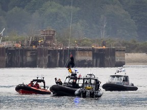 A protester opposed to the Kinder Morgan Trans Mountain pipeline expansion is lowered to a police boat, July 4, 2018, after spending two days suspended from the Second Narrows Bridge in Vancouver.