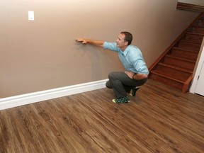 Chris DaSilva shows the height of wall he and his wife Patricia had to remove after flooding the first time.  Da Silva has replaced flooring with "100 percent waterproof floor."