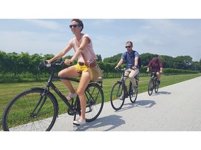 Farm Dog Cycles co-owner Meg Balsillie,  Alex Denonville, communications manager at Town of Essex and Nelson Silveira, economic development officer for the Town of Essex, ride County Road 50.