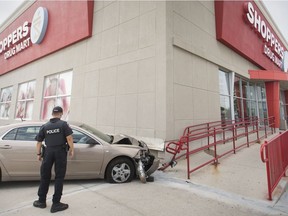 A Windsor police officer inspects a car that struck the side of the Shoppers Drug Mart at Market Square at the corner of Ottawa Street and Walker Road on Thursday, August 9, 2018.  Injuries appeared minor to the elderly woman driver.